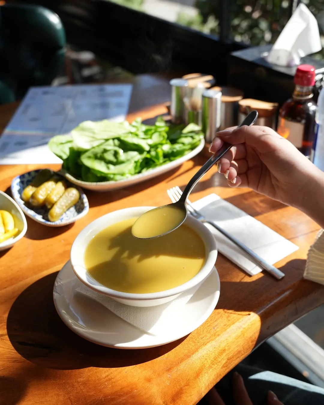 Süzme mercimek çorbası; yanında marul ve turşu